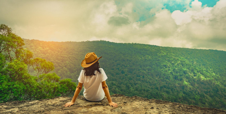 Woman wearing a hat sitting on a rocky cliff