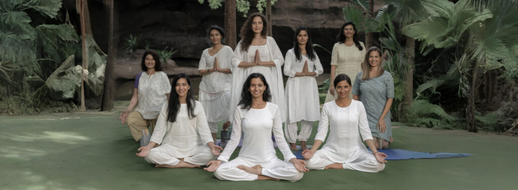 Group of people practicing yoga in India with natural landscape backdrop