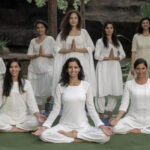Group of people practicing yoga in India with natural landscape backdrop