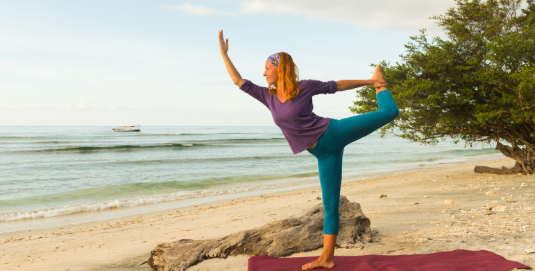 People practicing yoga on a sandy beach during sunrise in Goa