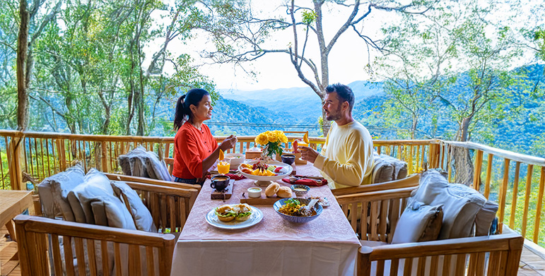 A peaceful dining pavilion overlooking a garden or mountain view, with guests eating mindfully.